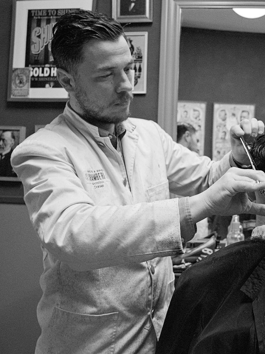 Barbier beim Haarschnitt mit Schere und Kamm